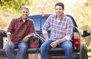 Two men sitting on back of truck