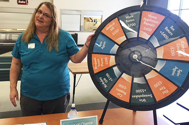 Woman standing next to spinning fortune wheel as part of financial reality fair day