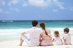 Family of four sitting on Caribbean beach