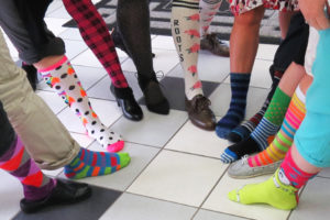 Group standing in a circle showing off their colorful socks on sock day