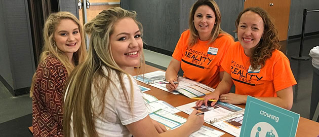 Two female employees and two high school students sitting at a table