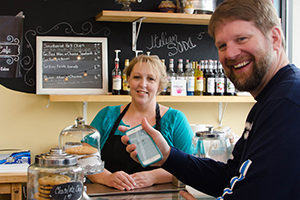 man at local bakery holding cell phone showing Go Local app