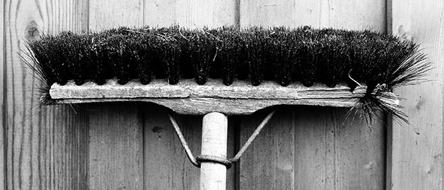 broom hanging on wooden wall