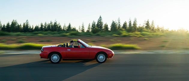 Car driving on open road with sun setting in background