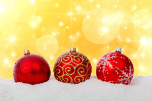 Red Christmas ornaments against a yellow backdrop