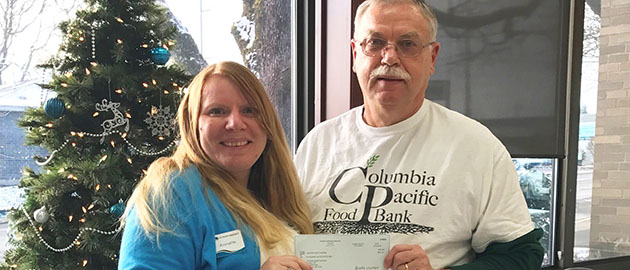 Happy female presents check to male director of food bank in front of christmas tree