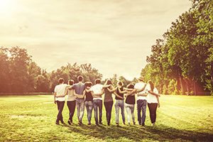 group of young adults walking together with arms around one another