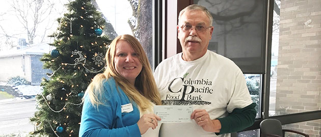 female employee presenting check to male representative of food bank