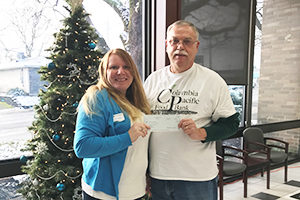 female employee presenting check to male representative of food bank