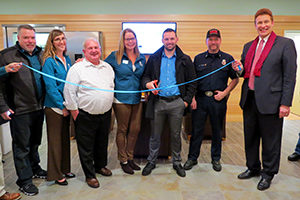 group of board and community members cutting a blue ribbon