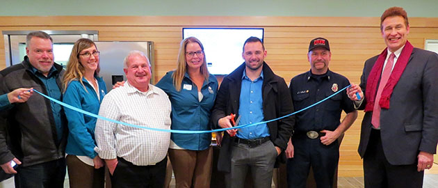 group of board and community members cutting a blue ribbon