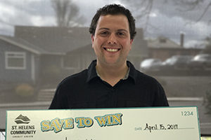 smiling young man holding a large check