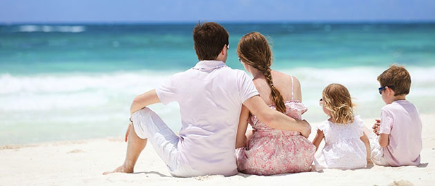 Family of four sitting on Caribbean beach