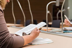 woman reading a book in college library