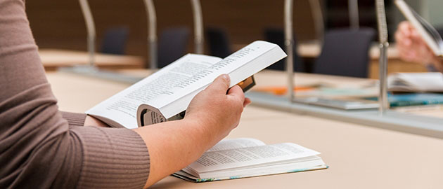 woman reading a book in college library