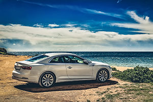 silver car sitting on hilltop overlooking beach