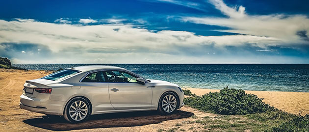 silver car sitting on hilltop overlooking beach