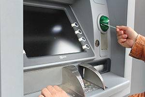 hand pushing a debit card into an atm machine