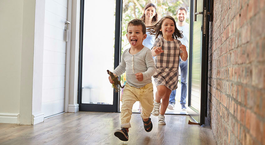 Excited Children Arriving Home With Parents