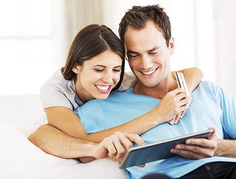Happy loving couple using tablet computer and credit card at home. Horizontal shot.