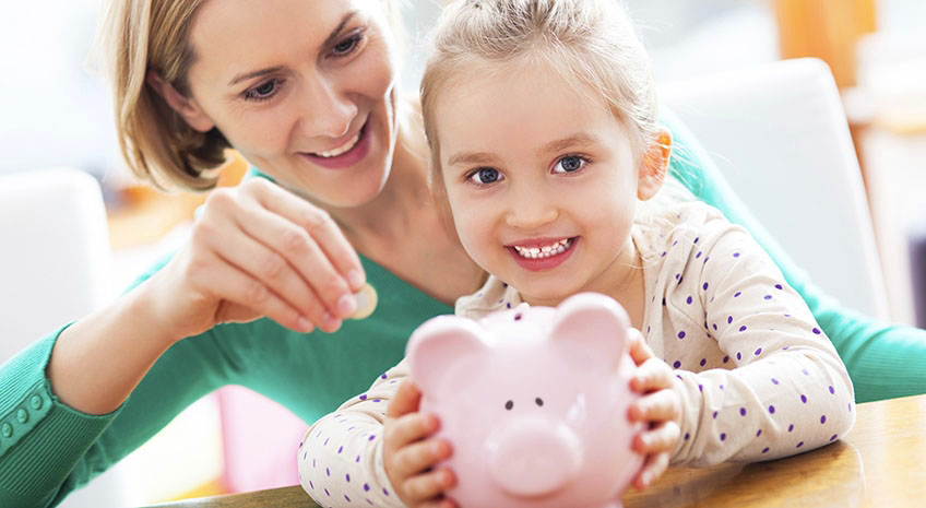 blonde haired young girl with her mother holding a piggy bank and smiling
