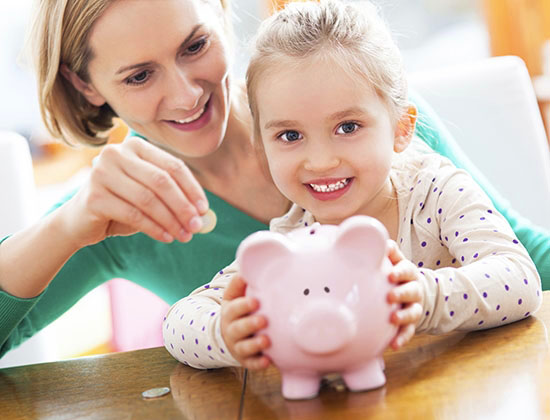 blonde haired young girl with her mother holding a piggy bank and smiling