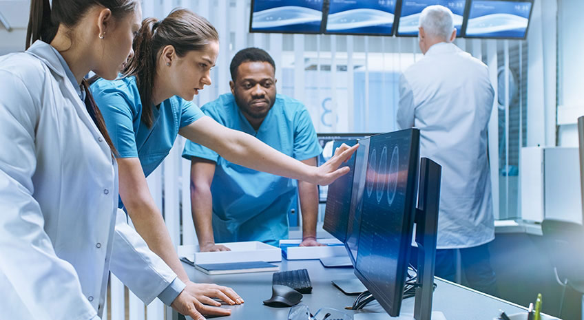 Diverse Team of Medical Scientists Solve Problems and Point at Computer Screens Showing CT, MRI Scans. Neurologists / Neuroscientists Working in Brain Research Laboratory.