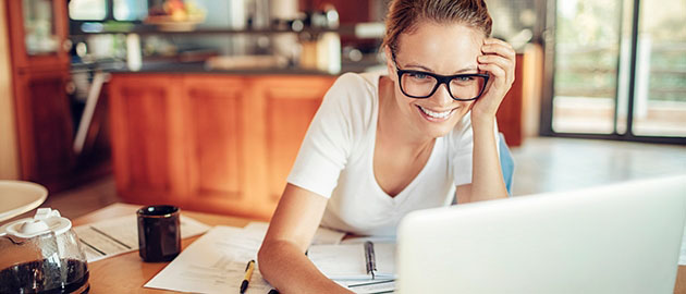 Close up of a woman using a laptop in the kitchen