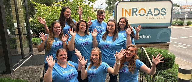 Group of young employees smiling and holding their hands in the air