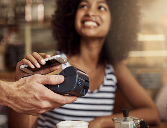 Woman paying for coffee with phone. Horizontal shot.