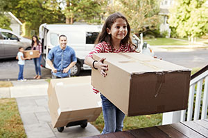 Children Helping Unload Boxes From Van On Family Moving In Day