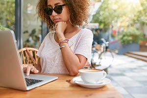 woman outdoors computer sunglasses coffee