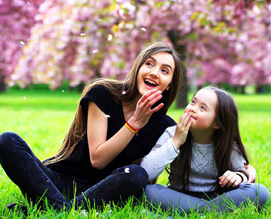 sisters sitting in grass with cherry blossom trees