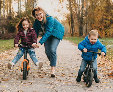 mom riding bikes with kids in autumn