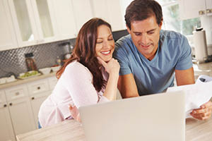 man woman finances kitchen laptop