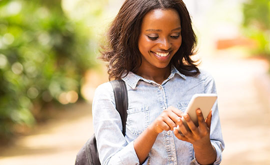 happy young african american uni student using cell phone