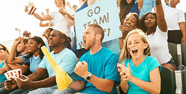 Excited crowd of fans cheering on team from stadium bleachers