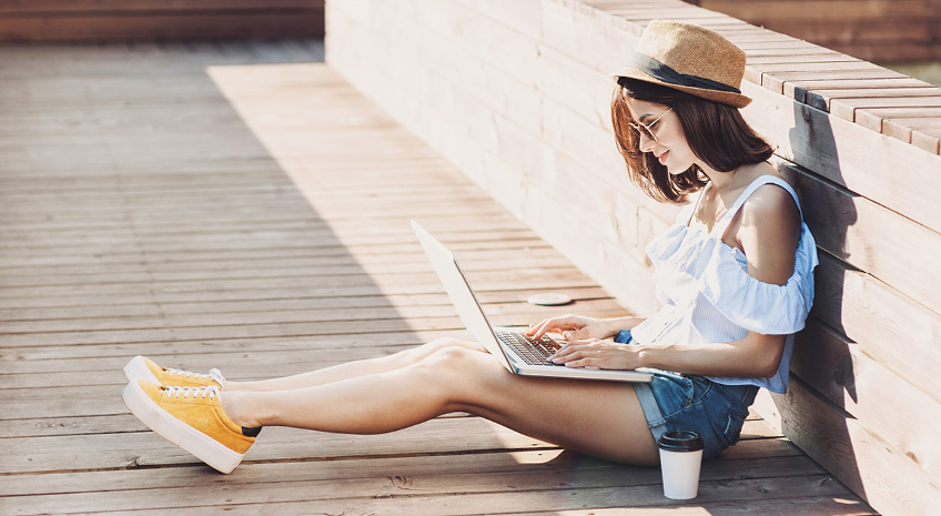 woman on laptop with coffee in a hat