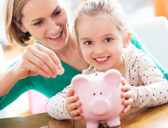 mother and daughter adding coins to a piggy bank
