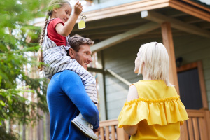 man, woman, and child standing outside home with house keys