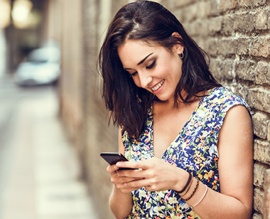 Smiling young woman using her smart phone outdoors