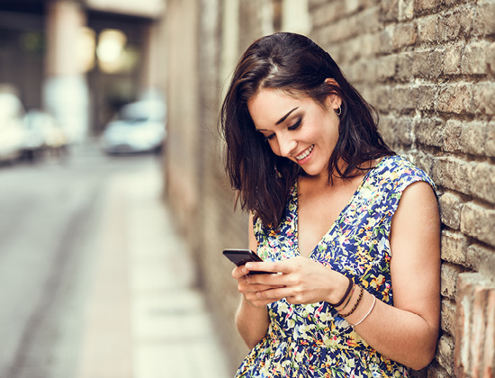 Smiling young woman using her smart phone outdoors