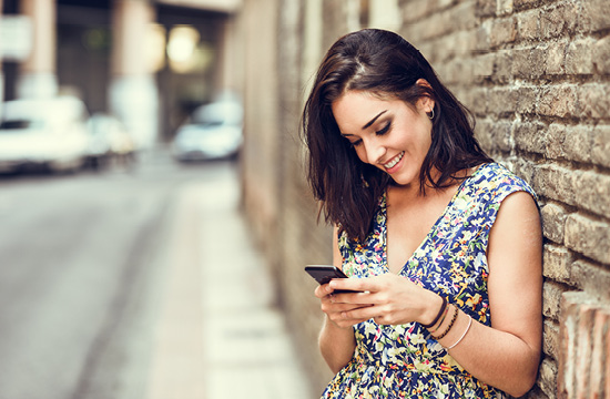 Smiling young woman using her smart phone outdoors