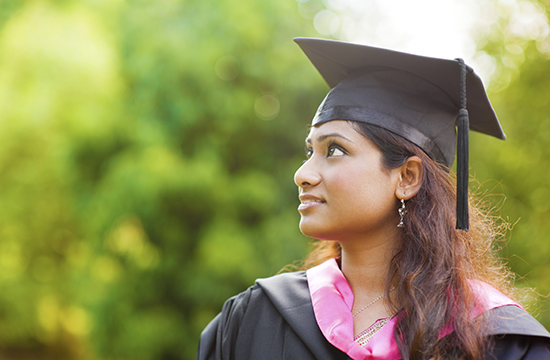 young adult woman in black graduation gown and black graduation cap