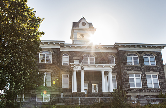 large brick columbia county courthouse with the sun rising behind the belltower