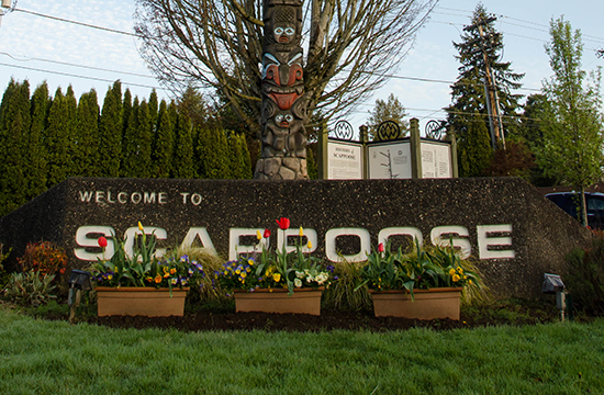 scappoose sign with totem pole and tree behind it