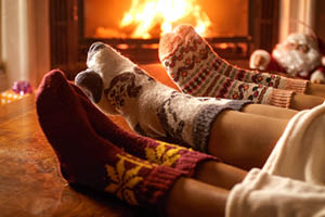 Closeup image of family wearing woolen socks warming by the fireplace