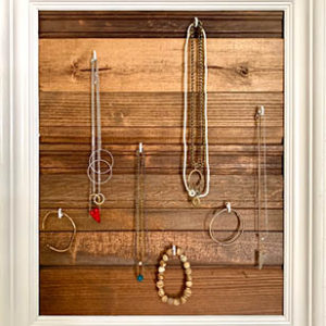 jewelry hanging from reclaimed wood in a frame for storage