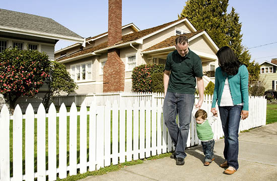 man and woman holding hands of small child while walking down a residential sidewalk