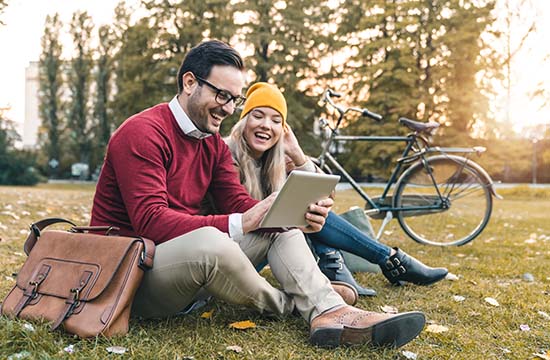 Young couple using tablet to shop while sitting in public park